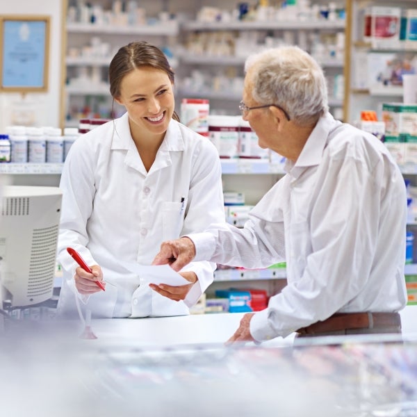 Senior redeems prescription with drink food in pharmacy with friendly pharmacist