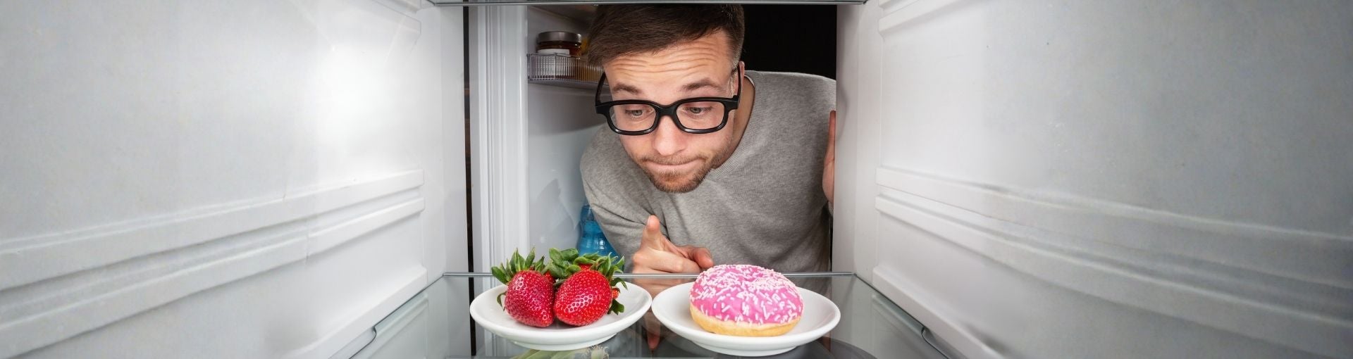 Mann greift im Kühlschrank zu