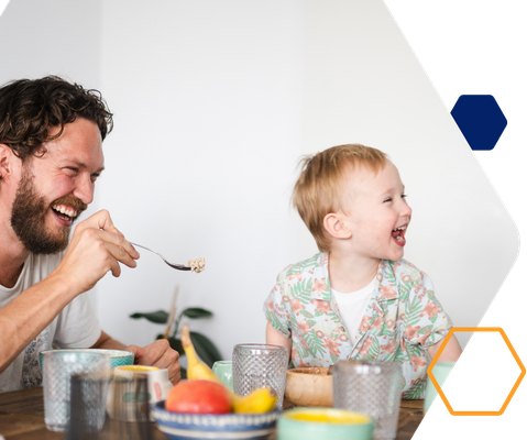 Erwachsene Person und Kind essen gemeinsam an einem Tisch