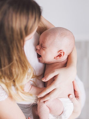 Baby crying in arms of mother Baby crying in arms of mother