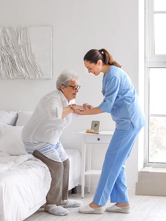 young caregiver helps old women to stand