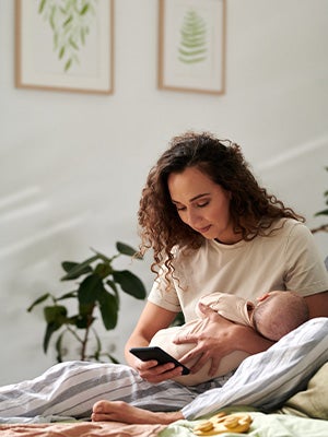 mother with baby on hands texting with mobile phone