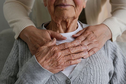 Young woman holding hands of old woman